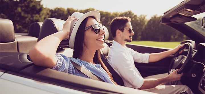 Beautiful young couple sitting in their car and enjoying in the road trip. The focus is on the woman.